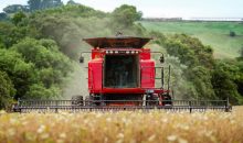 pexels-photo-27089345-27089345 A red combine harvester in action during summer harvest in a lush green countryside.